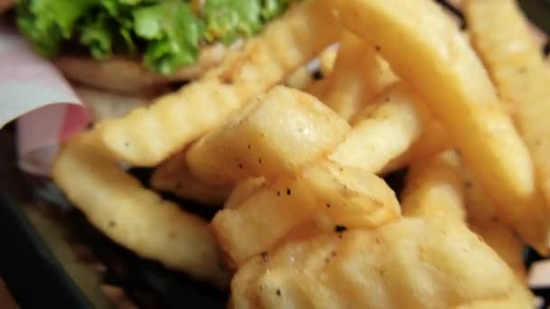 Închidere de cartofi prăjiți și hamburger într-un coș negru — Videoclip de stoc