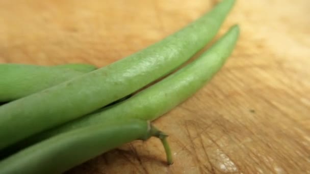 Grüne Bohnen isoliert auf einem zerkratzten Holztisch — Stockvideo