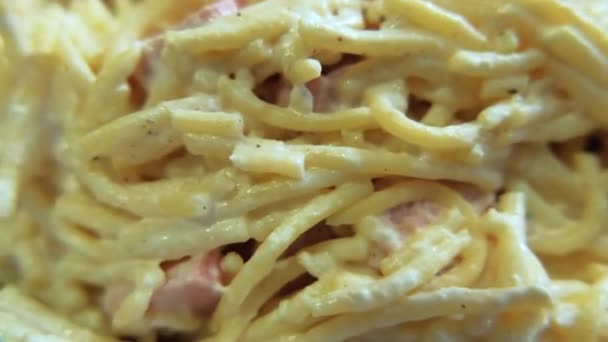 Spaghetti mit weißer Soße und Schinkenscheiben auf einem Teller — Stockvideo