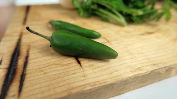 Зеленый перец чили и кориандр на разделочной доске — стоковое видео