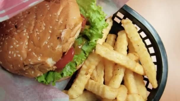 Close-up de batatas fritas e hambúrguer em uma cesta preta — Vídeo de Stock