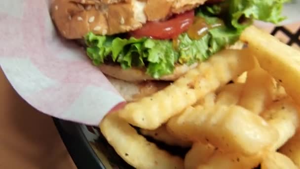 Close-up de batatas fritas e hambúrguer em uma cesta preta — Vídeo de Stock