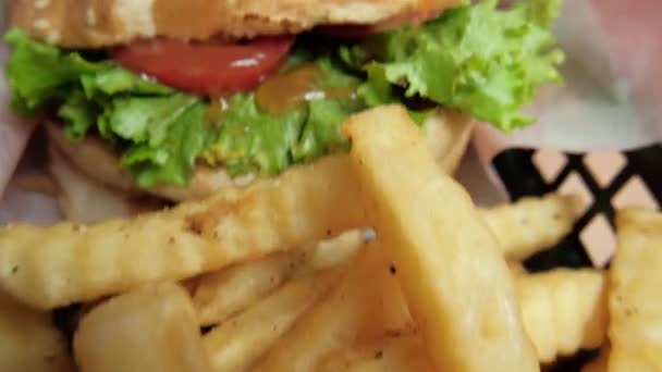 Close-up van friet en hamburger in een zwarte mand — Stockvideo