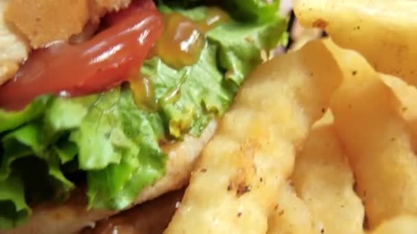 Close-up kentang goreng dan hamburger dalam keranjang hitam — Stok Video