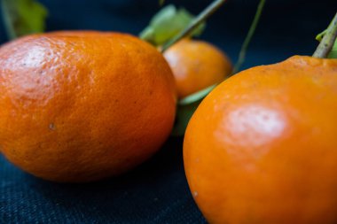 Siyah masa örtüsü olan bir masada izole edilmiş mandalinalar.