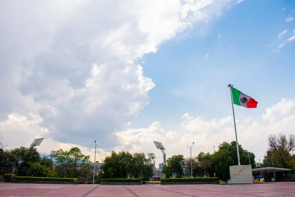 Bandera mexicana ondulada en plaza pública con un cielo nublado como fondo —  Fotos de Stock