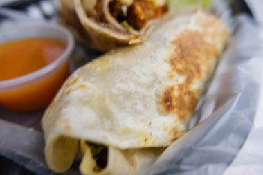 Plastik sepette baharatlı domuz burrito ve marul.
