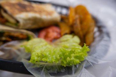 Plastik sepette baharatlı domuz burrito ve marul.