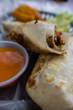 Plastik sepette baharatlı domuz burrito ve marul.