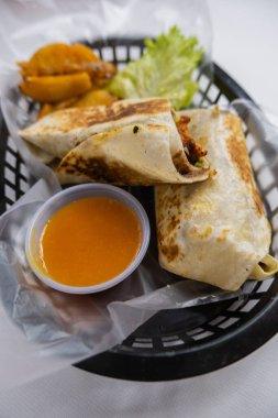 Plastik sepette baharatlı domuz burrito ve marul.