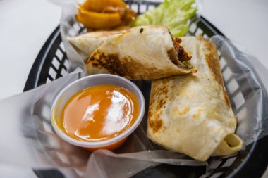 Plastik sepette baharatlı domuz burrito ve marul.