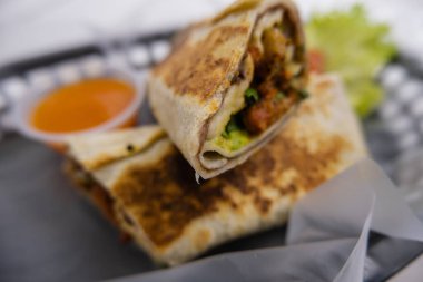 Baharatlı domuz dürümü ve plastik sepetteki sos.