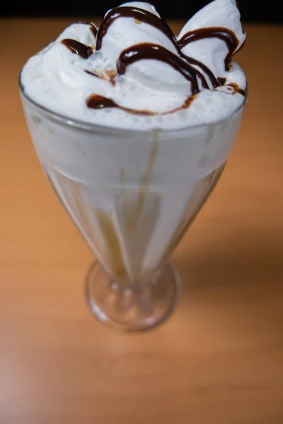 Vanilla milkshake with chocolate syrup on a table