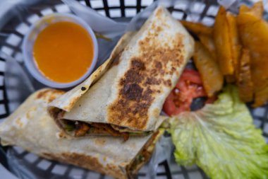 Plastik sepette baharatlı domuz burrito ve marul.