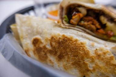 Baharatlı domuz dürümü ve plastik sepetteki sos.