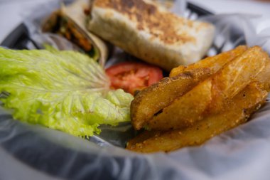 Plastik sepette baharatlı domuz burrito ve marul.