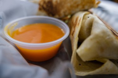 Plastik sepette baharatlı domuz burrito ve sos.