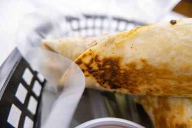 Plastik sepette baharatlı domuz burrito ve sos.