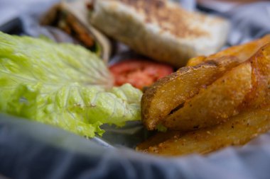 Plastik sepette baharatlı domuz burrito ve marul.