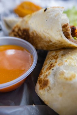 Plastik sepette baharatlı domuz burrito ve marul.