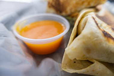 Baharatlı domuz dürümü ve plastik sepetteki sos.