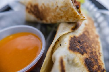 Plastik sepette baharatlı domuz burrito ve sos.