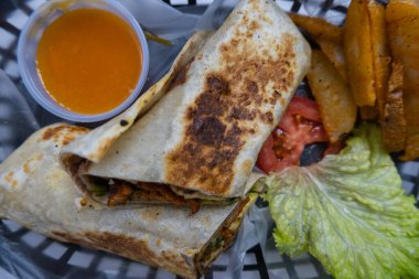 Plastik sepette baharatlı domuz burrito ve marul.