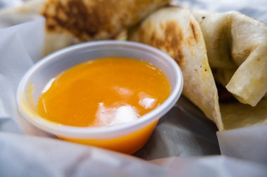 Baharatlı domuz dürümü ve plastik sepetteki sos.