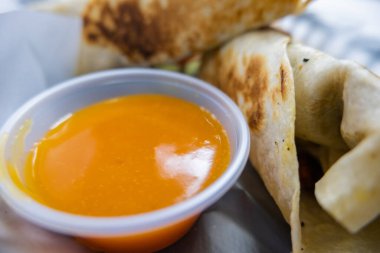 Baharatlı domuz dürümü ve plastik sepetteki sos.