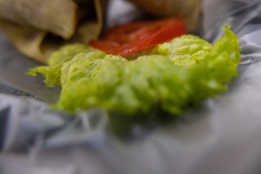 Plastik sepette baharatlı domuz burrito ve marul.