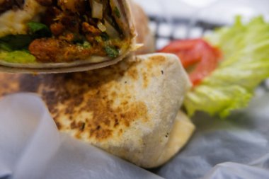 Plastik sepette baharatlı domuz burrito ve marul.