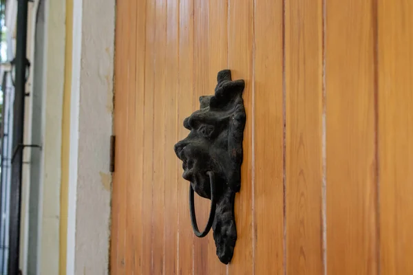 Old metal door knocker on a wooden door