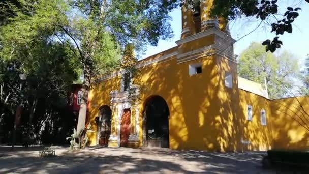 Alte mexikanische Kirche umgeben von Bäumen in Coyoacan — Stockvideo