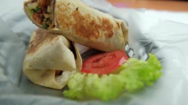 Plastik sepette baharatlı domuz burrito ve marul.