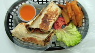 Plastik sepette baharatlı domuz burrito ve marul.