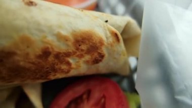 Plastik sepette baharatlı domuz burrito ve marul.