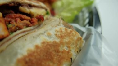 Plastik sepette baharatlı domuz burrito ve marul.