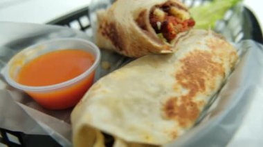Plastik sepette baharatlı domuz burrito ve marul.