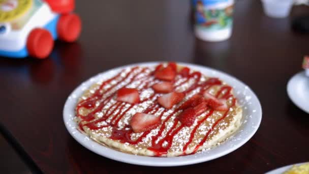 Pancake with strawberry slices and syrup on a white plate — Stock Video