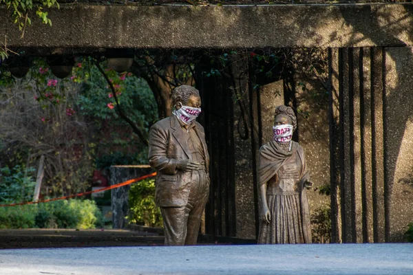 Statues of sitting Frida Kahlo and Diego Rivera wearing face masks — Stock Photo, Image