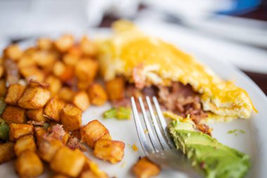 Yarısı yenmiş omlet ve beyaz tabakta kızarmış patates.