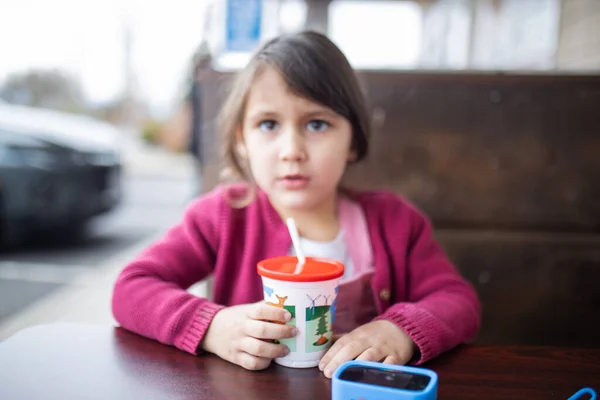 Милая маленькая девочка пьет из чашки с соломой — стоковое фото