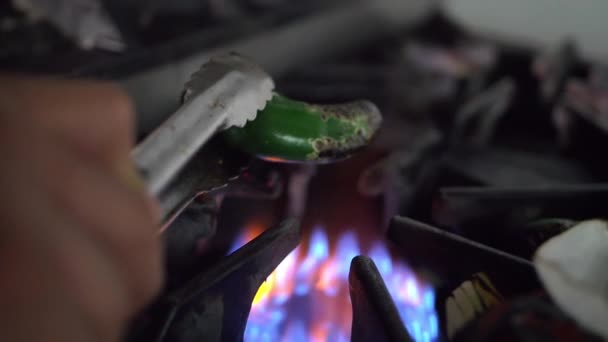 Mão assar pimenta com pinças de aço sobre um queimador aberto — Vídeo de Stock