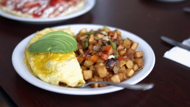 Omelette, Bratkartoffeln und Avocadoscheiben auf einem weißen Teller — Stockvideo