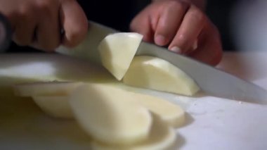 Kadın aşçının elleri yavaşça patatesi doğruyor.