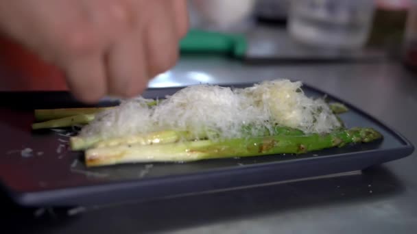 Male hand sprinkling grated onions on top of roasted asparagus — Stock Video