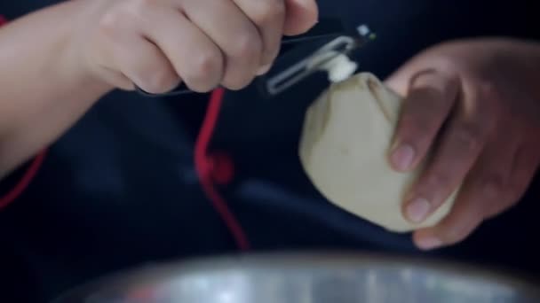 As mãos do cozinheiro feminino lentamente descascando uma batata — Vídeo de Stock