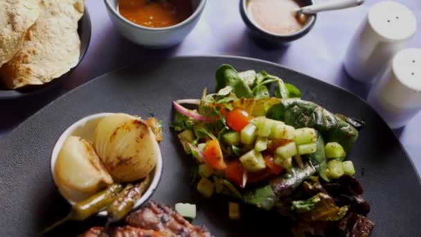 Gegrilltes Fleisch, Salat, geröstete Zwiebeln und Chilischoten auf dem Teller — Stockvideo