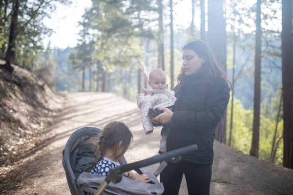 Donna felice che tiene il suo adorabile bambino nella foresta — Foto Stock