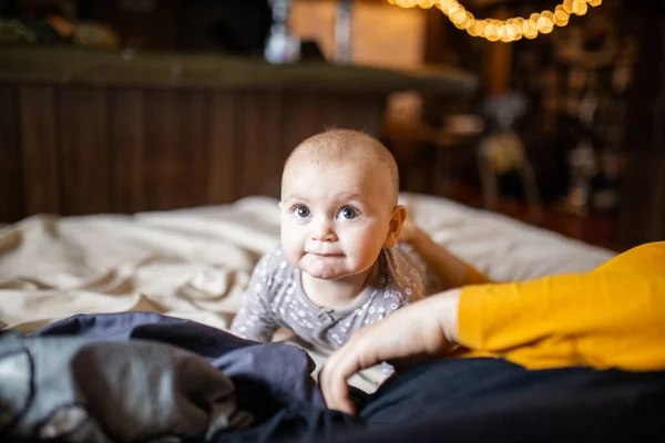 Bebê adorável e feliz deitado no estômago acima de uma cama — Fotografia de Stock